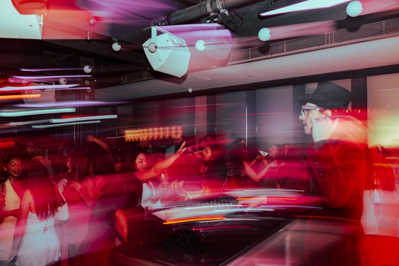 DJ and dancefloor streaked with red and purple light trails
