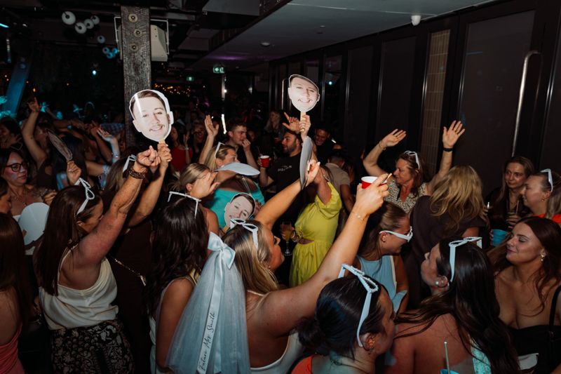 Hens party dancing with cut-out faces of the groom
