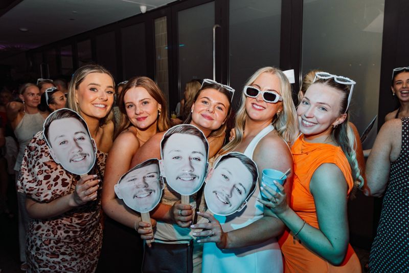 Bride and friends posing with cut-out faces of the groom