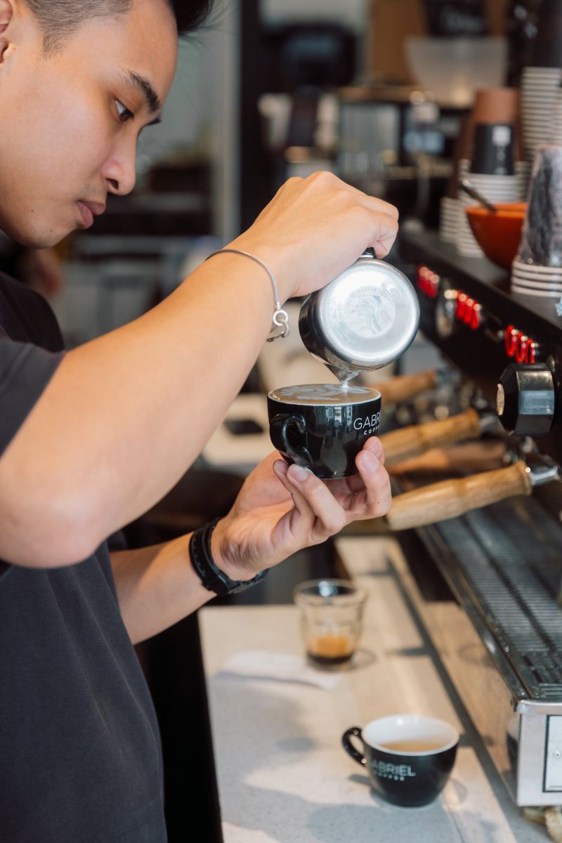 Barista pouring latte art into a Gabriel Coffee cup