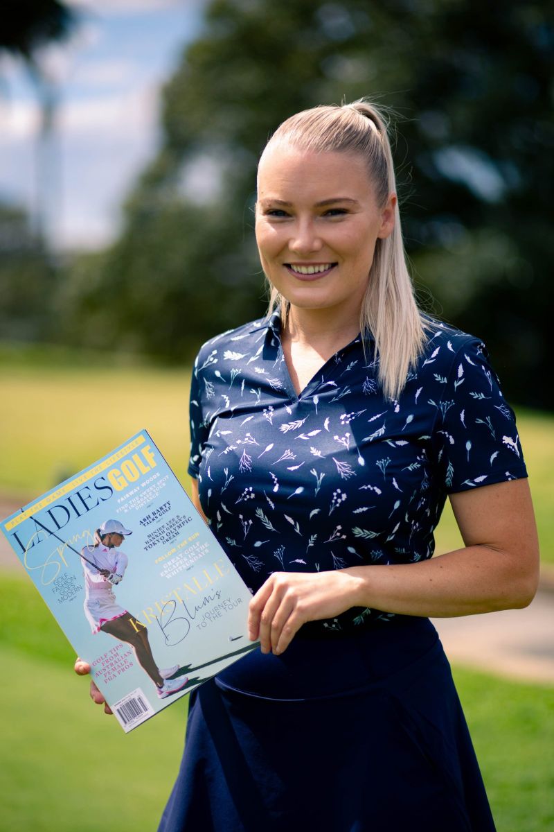 Golfer smiling with a copy of the magazine on the course